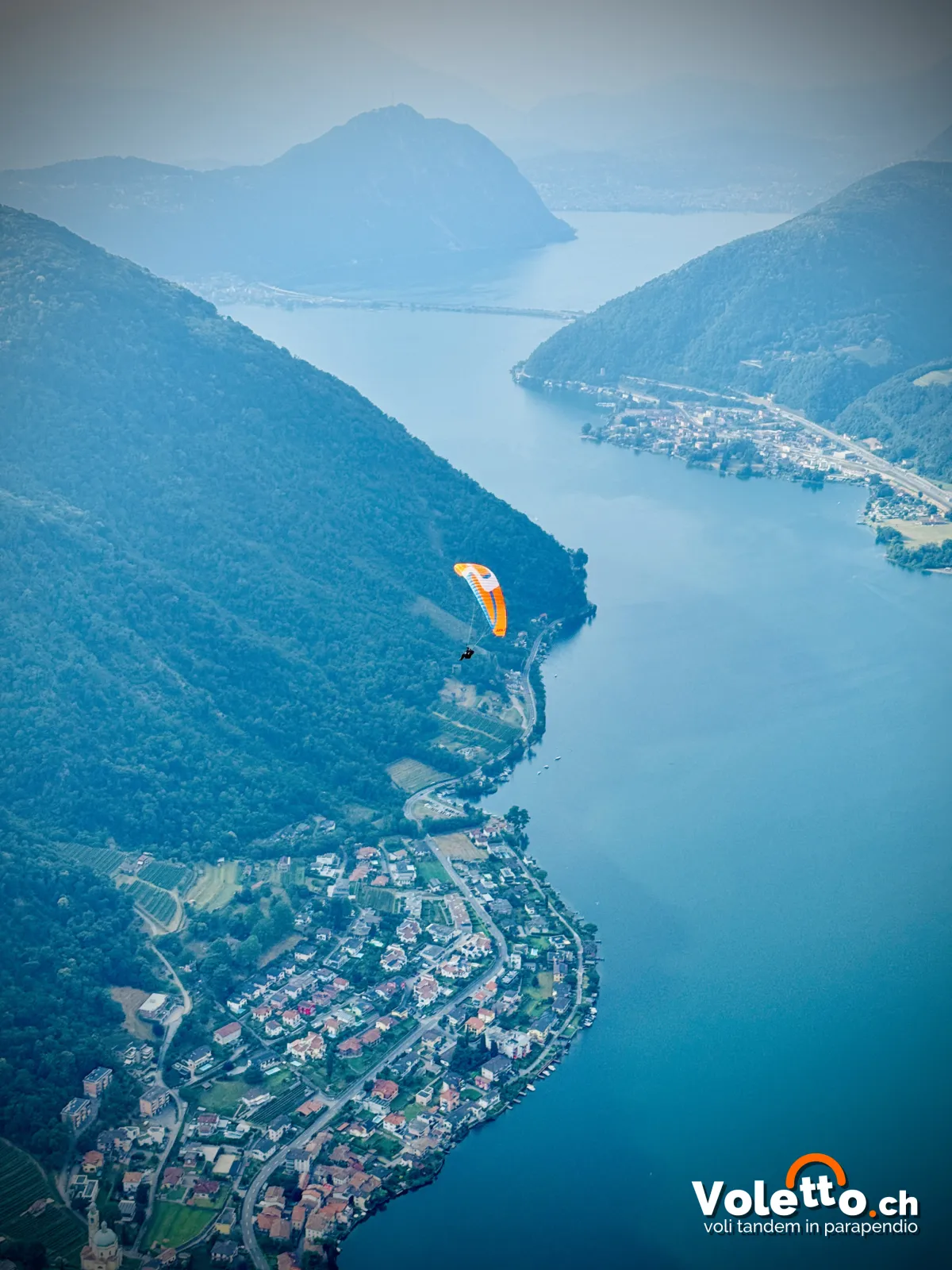 Parapendio in volo sopra il Lago di Lugano e Capolago
